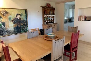 A dining room with a wooden table, six chairs, and a decorative bowl on the table. - Stunning 6 Bedroom Riverside Barn Cotswold Mill (Cirencester)