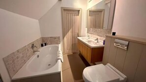 A bathroom with a bathtub, a sink, and a toilet. - Stunning 6 Bedroom Riverside Barn Cotswold Mill (Cirencester)