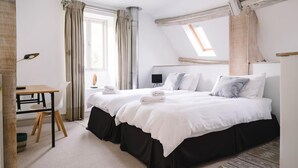 A bedroom with two beds, a desk, and a window with curtains. - Stunning 6 Bedroom Riverside Barn Cotswold Mill (Cirencester)