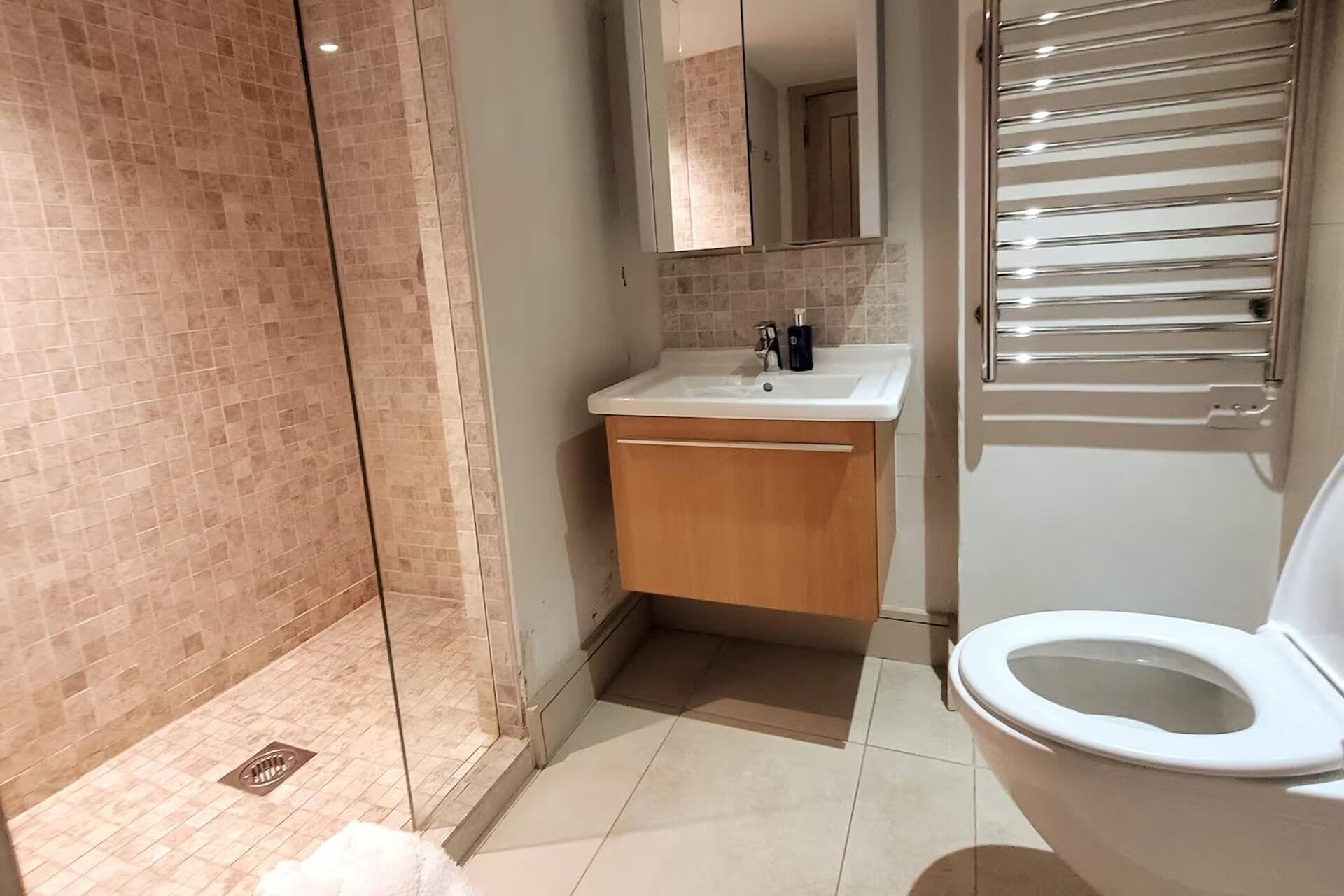 A modern bathroom with a glass shower enclosure, a wooden vanity with a sink, and a toilet.