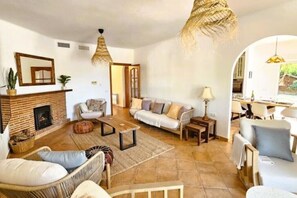 A spacious living room with a fireplace, sofas, and a dining area.