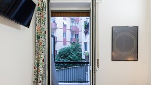 A doorway leading to a balcony with a view of a multi-story building and a tree. - notaMI - Welcome Darsena (Milan)