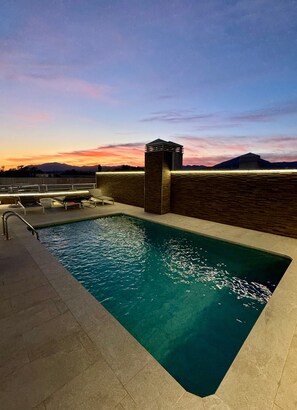 A swimming pool with a view of mountains at sunset.