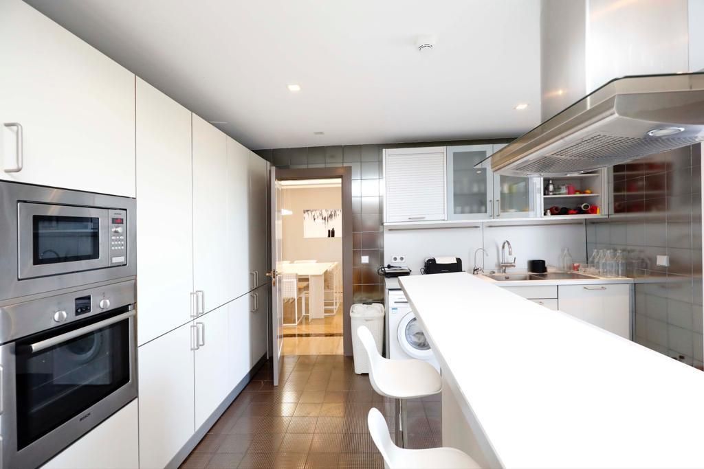 A modern kitchen with stainless steel appliances, a central island, and a view into the dining area.