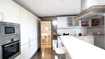 A modern kitchen with stainless steel appliances, a central island, and a view into the dining area.