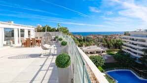 Une terrasse sur le toit comprenant un espace repas, une piscine et une vue sur la mer et le paysage urbain.