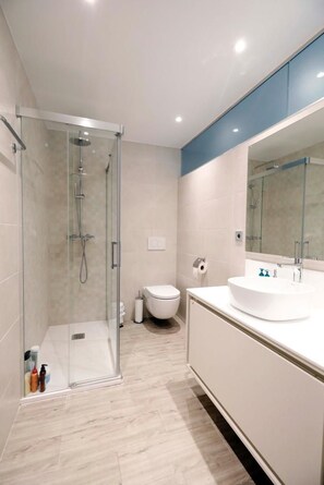 A modern bathroom with a glass-enclosed shower, a white sink, and a large mirror. - Private Rooftop Pool & Spa, Puerto Banús Seafront (Marbella)