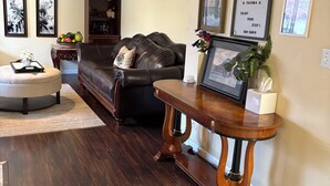 Ein Wohnzimmer mit dunklem Holzboden, einer Ledersofa, einem Holztisch und einem an der Wand befestigten Schild.