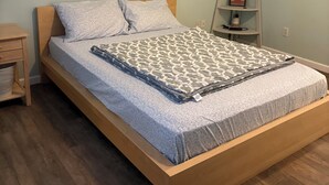 Ein Einzelbett mit einem gemusterten Bettbezug, einem hölzernen Kopfteil und einem Nachttisch mit einer Lampe.