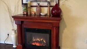 A fireplace with a framed picture above it, a vase, and a bowl on the mantel. - Fantastic 4-bedroom house with AC in charming Tacoma, the heart of Puget Sound. (Tacoma)