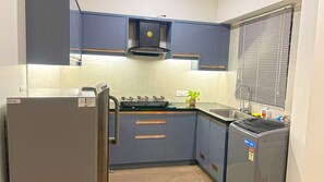 Une cuisine de taille réduite avec des meubles gris, une cuisinière encastrée et un réfrigérateur.
