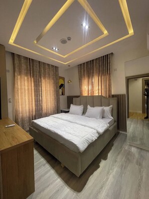 Een moderne hotelkamer met een groot bed, een houten bureau en een spiegel.