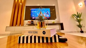 Moderni olohuone, jossa on litteänäyttöinen televisio, koristeellinen kasvi ja puupöydällä kirja, jonka nimi on ”NEW YORK”.