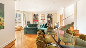 A spacious living room with a green sofa, a glass coffee table, and a staircase leading to an upper floor. - Casa Colonna, a Burghesius home (Roma)