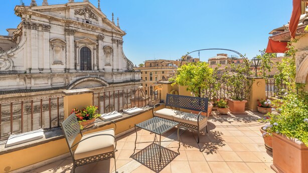 A rooftop terrace with outdoor seating, potted plants, and a view of a historic building. - Casa Colonna, a Burghesius home (Roma)