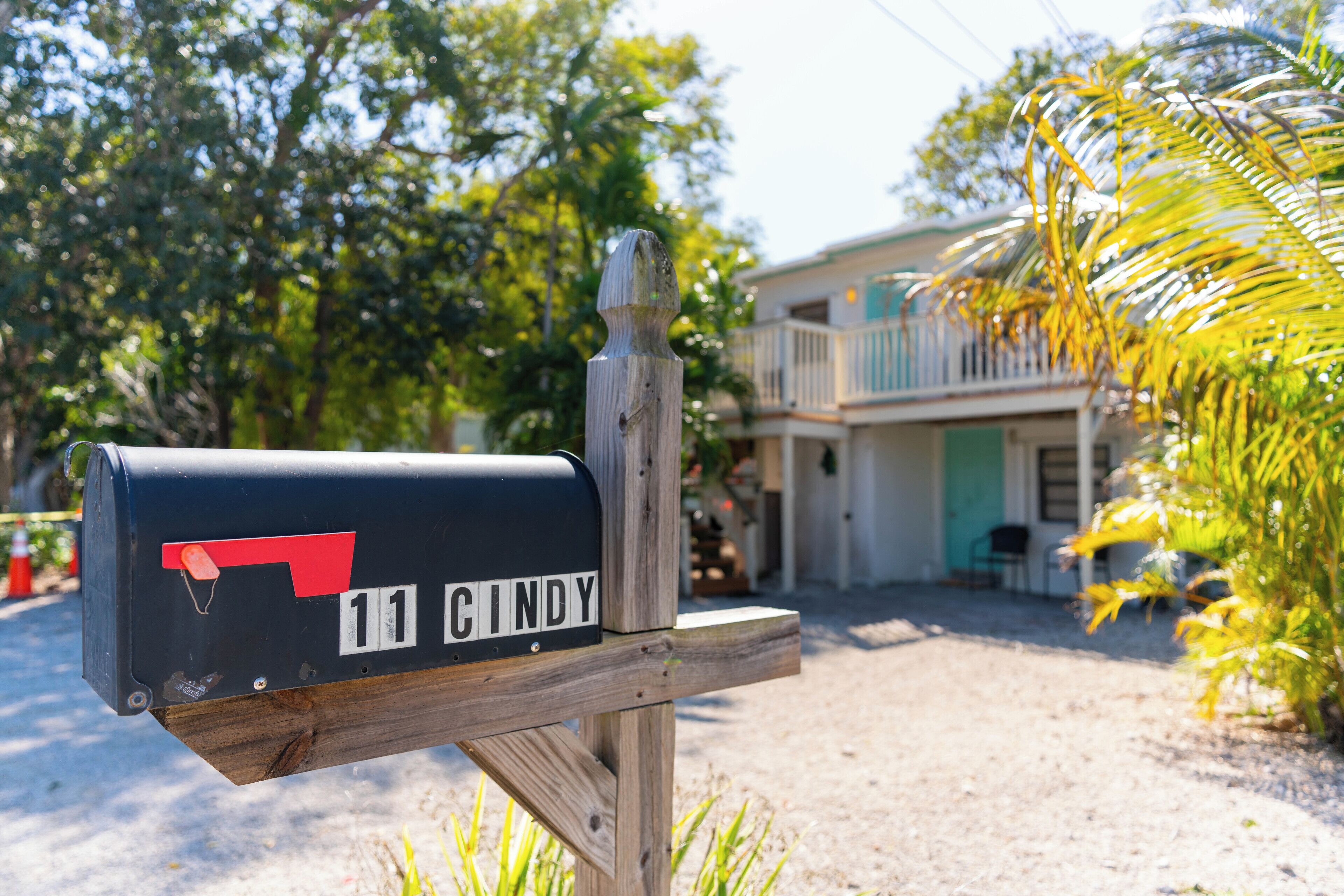 A mailbox with the name "11 CINDY" on a wooden post.