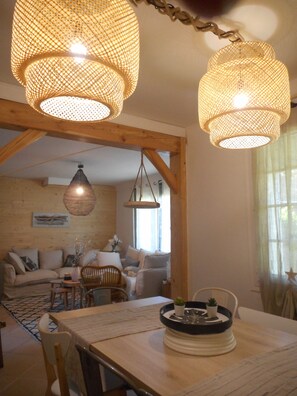 A cozy living room with a wooden ceiling, a dining table with chairs, and a hanging light fixture. - La maison des muriers in a peaceful setting (Mimizan)