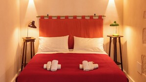 Ein Bett mit roter Decke, zwei Nachttische und ein Wandbogen.