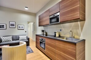 A modern kitchen with wooden cabinets, a built-in oven, and a stainless steel sink. - 140 - Urban Duplex near Saint-Germain des Pres (París)
