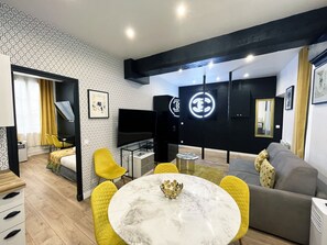 A modern hotel room with a dining area, a sofa, a TV, and a black wardrobe with a mirror. - 157 - Urban By Coco Flat in Montorgueil (París)