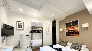Ein Hotelzimmer mit Bett, Fernseher, Heizung, Kleiderständer und Blick auf die Stadt.