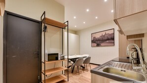 Eine moderne Küche mit Spüle aus Edelstahl, einem Essbereich mit Tisch und Stühlen sowie einem Stadtbild an der Wand.