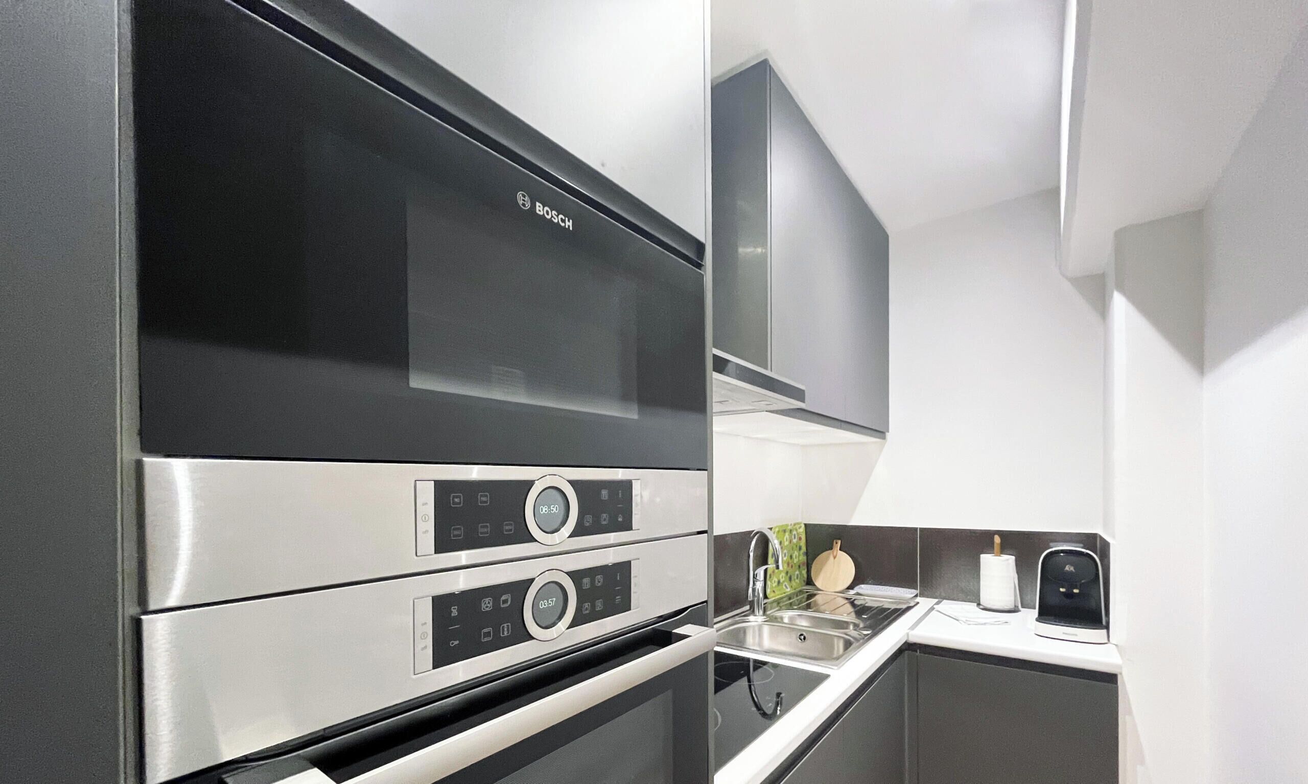 A kitchen with a Bosch range hood, a stainless steel oven, and a modern faucet.