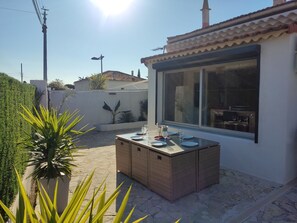 Eine Terrasse mit Esstisch, großes Fenster und Blick auf die Umgebung.