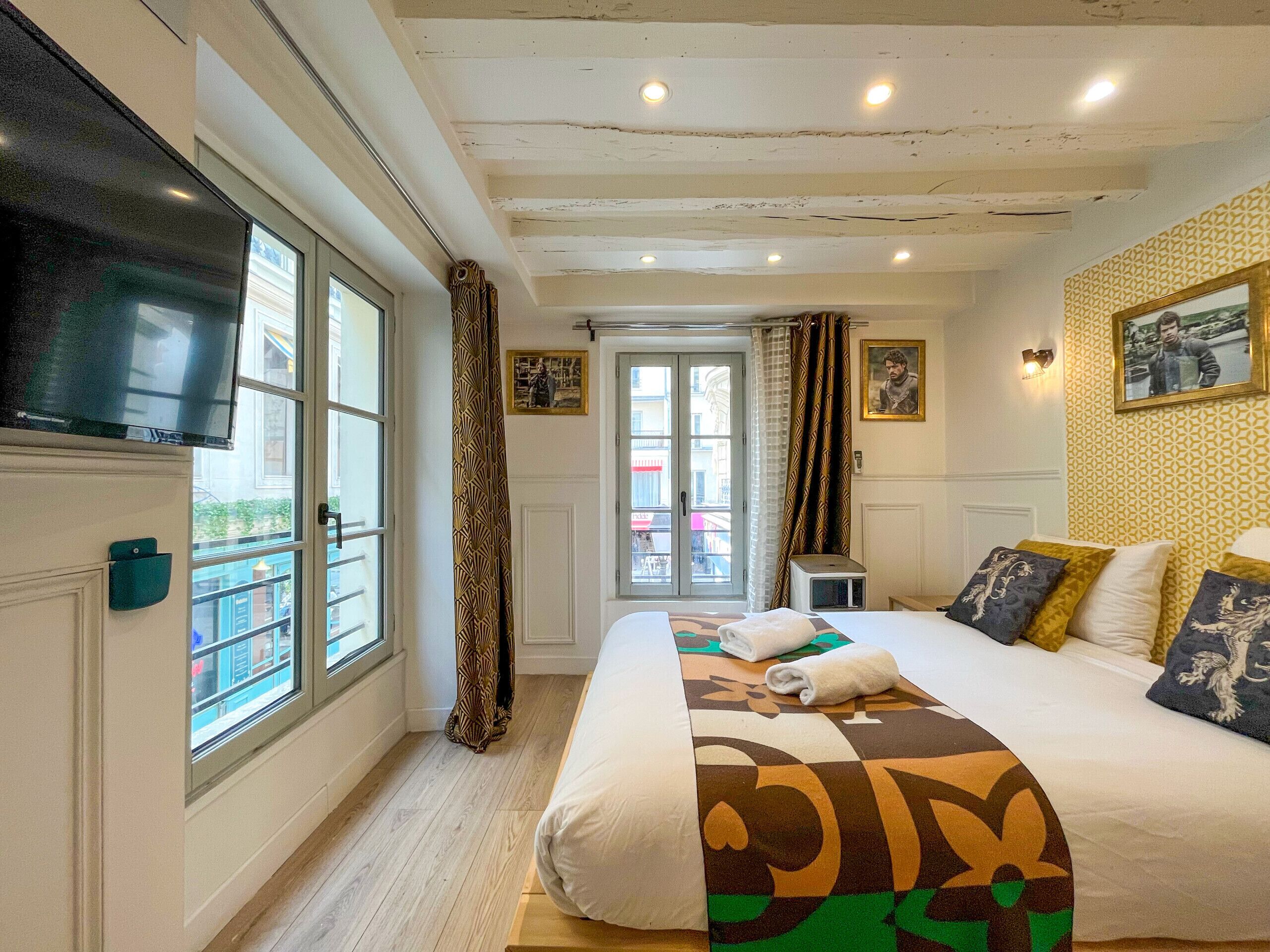 Ein Hotelzimmer mit Bett, Fernseher, Fenster und einer Tür, die auf einen Balkon führt.