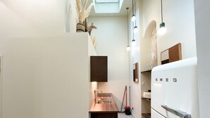 Une cuisine moderne équipée d’un four encastré, d’un évier et d’un plan de travail. Une fenêtre se trouve au-dessus de l’évier et un luminaire est suspendu au plafond.