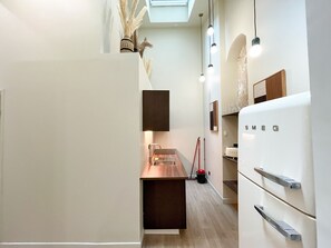 Eine moderne Küche mit Backofen, Spüle und Arbeitsplatte. Über der Spüle befindet sich ein Fenster und von der Decke hängt eine Leuchte.