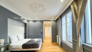 Ein Schlafzimmer mit Bett, Nachttisch, Heizkörper und einem Fenster mit Vorhängen.