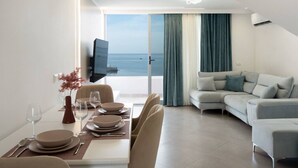 Ein modernes Wohnzimmer mit Essbereich, einer Couch und Meerblick.