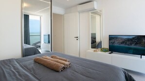 Ein modernes Hotelzimmer mit Bett, Fernseher und Balkon mit Meerblick.