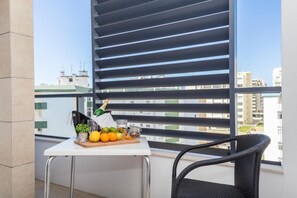 A balcony with a table set with fruits, a bottle, and a glass, overlooking a cityscape. - Modern Apartment with Ocean View | Right on the Beach at Praia da Rocha (Faro)