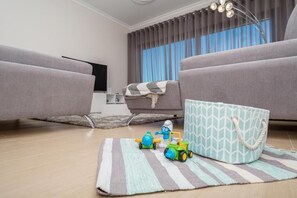 A modern living room with two grey sofas, a striped rug, and children's toys on the floor. - Modern Apartment with Sea View | First Line of Praia da Rocha (Faro)