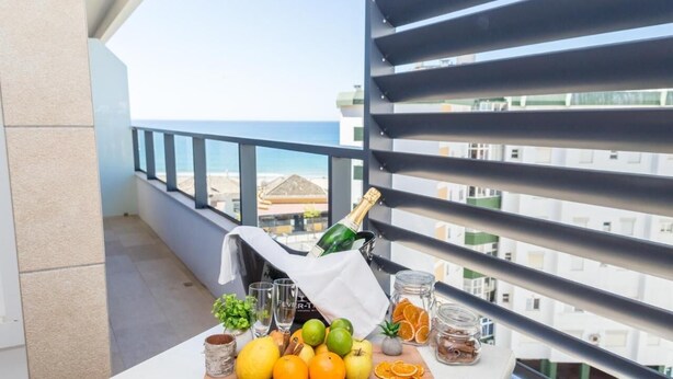 Een balkon met een tafel, daarop fruit, een champagnefles en een glas.