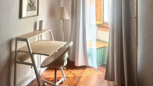 Ein Zimmer mit Schreibtisch, Stuhl, Lampe und einem gerahmten Bild an der Wand.