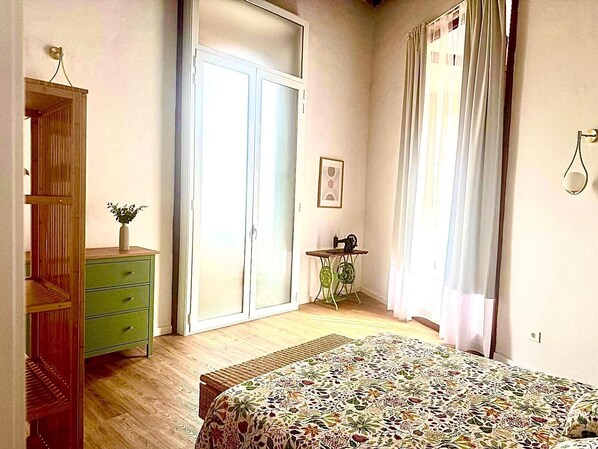 Une chambre à coucher avec un lit, une commode, une machine à coudre posée sur une petite table et une porte coulissante.