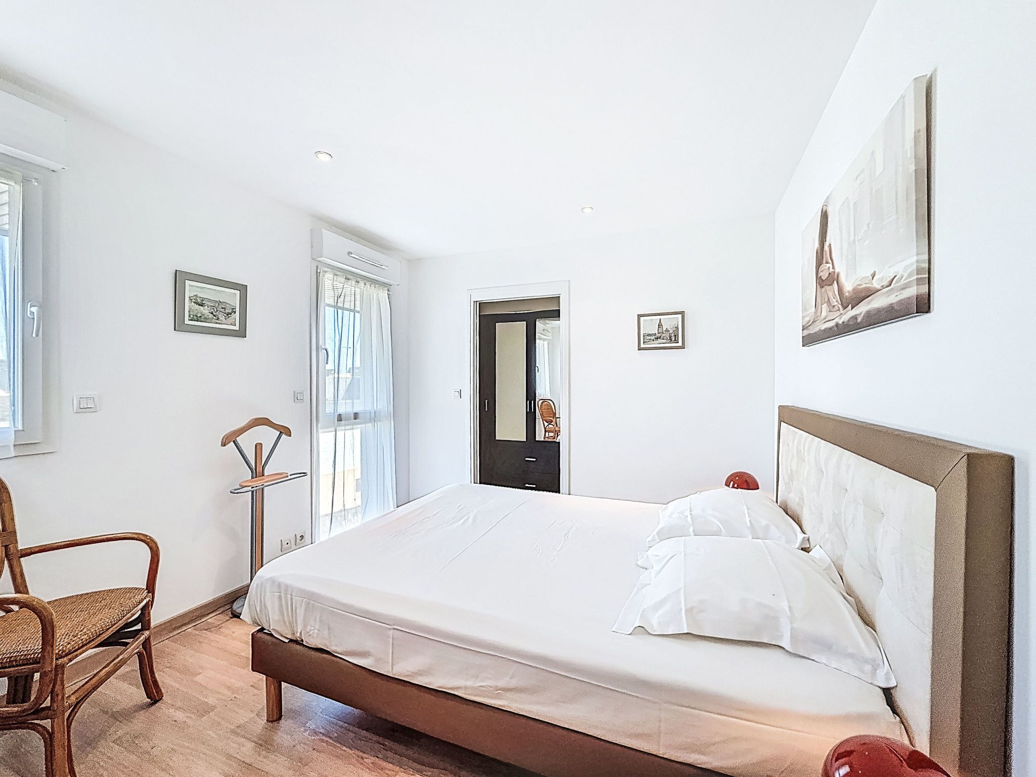 A bedroom with a bed, a chair, a door, and a window.