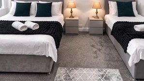 Een hotelkamer met twee bedden, nachtkastjes met lampen, een kamerkleed met patroon en twee posters aan de muur.