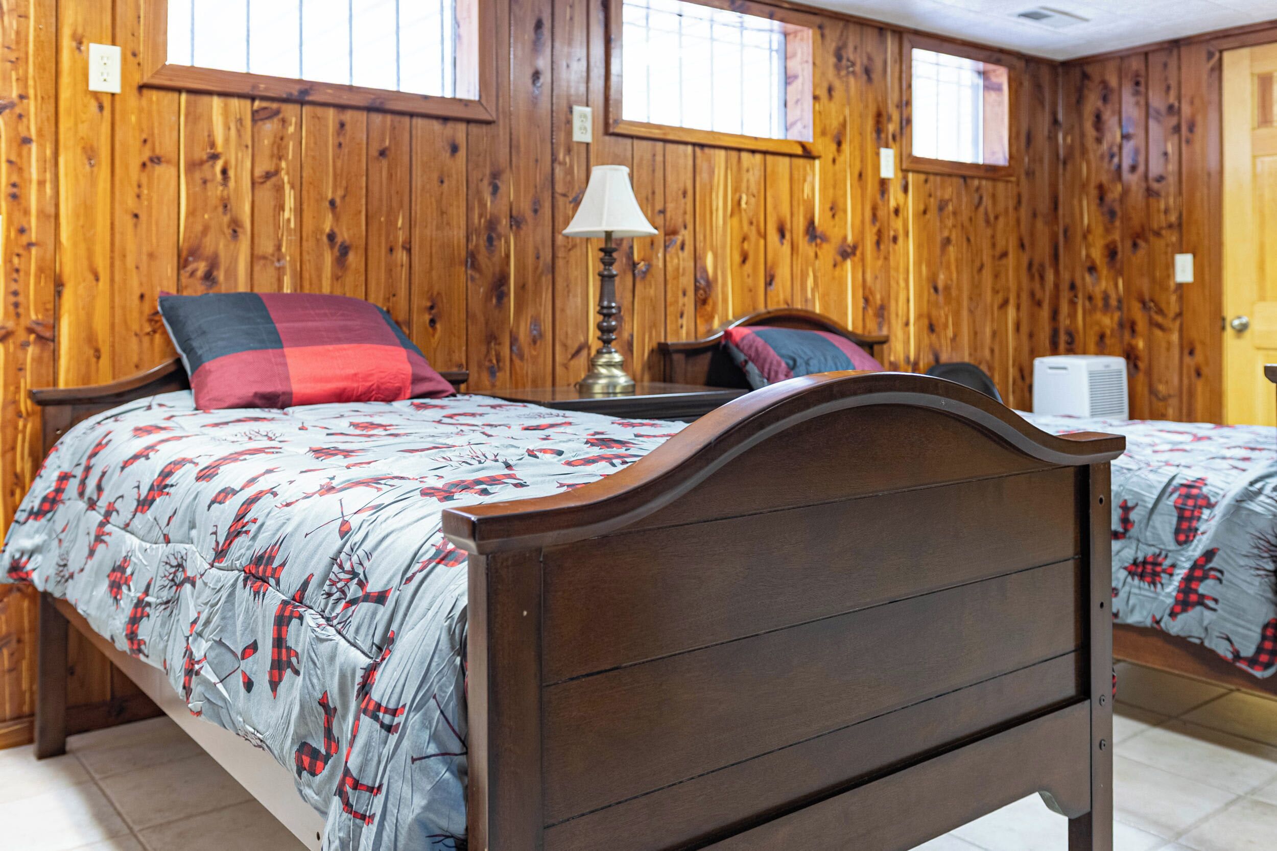 Ein Zimmer mit Holzwänden und zwei Betten, jeweils mit einem gemusterten Bettüberwurf.