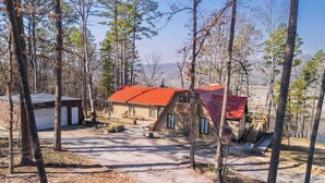 A cabin with a red roof, surrounded by trees, and a small deck area. - White River Escape with BBQ & Private Backyard (Norfork)
