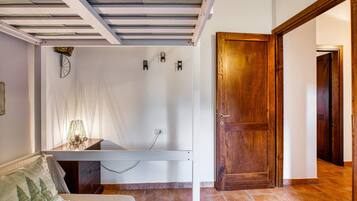 Ein Zimmer mit einem Bett, einem Schreibtisch, einer Holztür und einem gefliesten Boden.