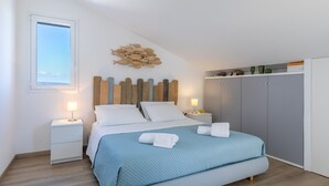 Een slaapkamer met een bed, nachtkastjes, een kledingkast en een visdecoratie aan de muur.