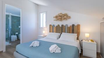 A hotel room with a bed, a nightstand, a wall-mounted fish decoration, and a bathroom visible through an open door.
