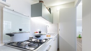 Een moderne keuken met een gasfornuis, twee pannen, een spoelbak en witte keukenkastjes.