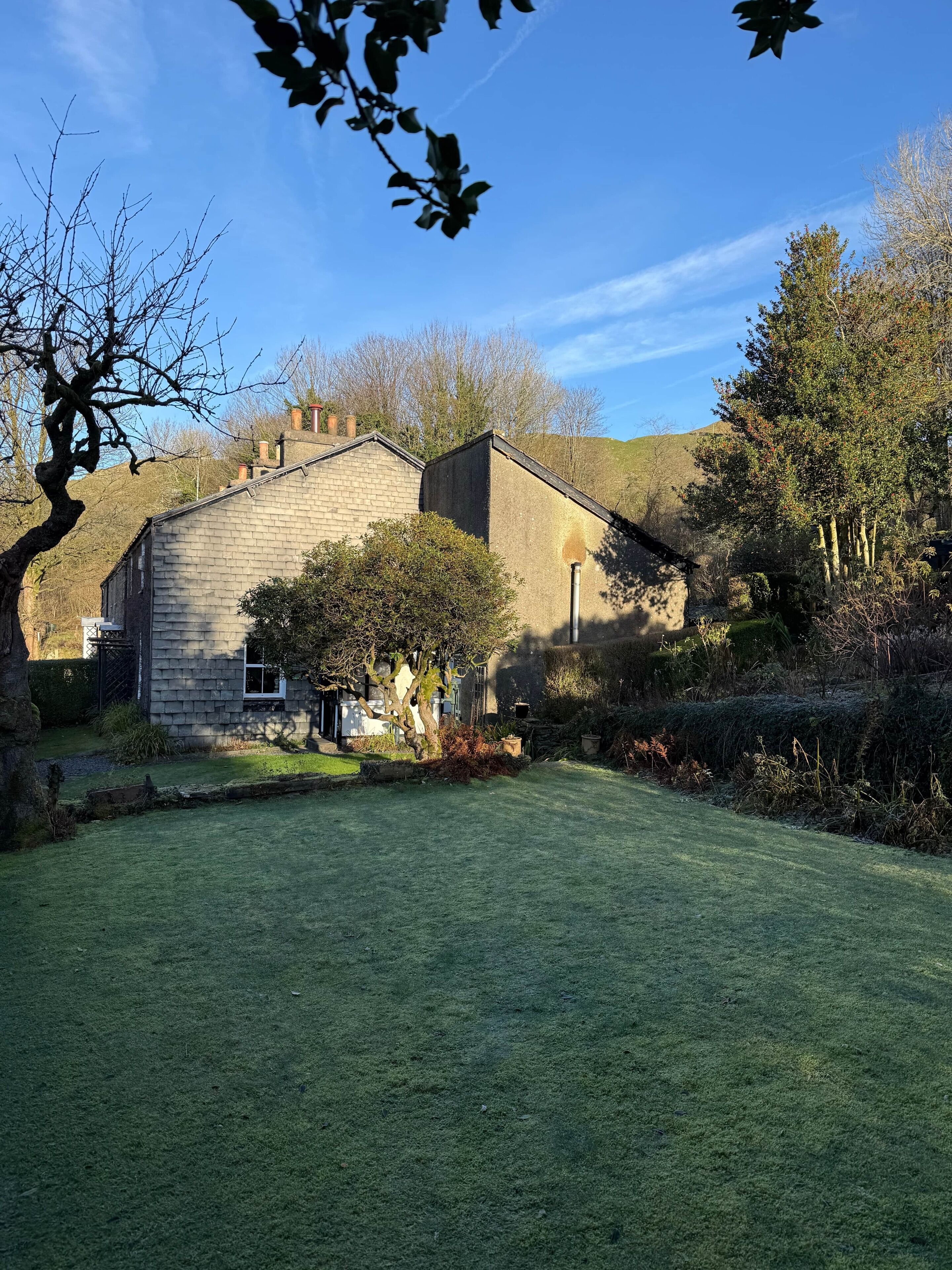 A stone house with a well-maintained lawn and surrounding trees.