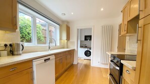A modern kitchen with wooden cabinets, a dishwasher, a washing machine, and a stove.