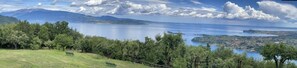 A panoramic view of a lake with mountains in the background, a grassy area with a bench, and a line of trees. - la FIOCCHINA magic place  (Salò)